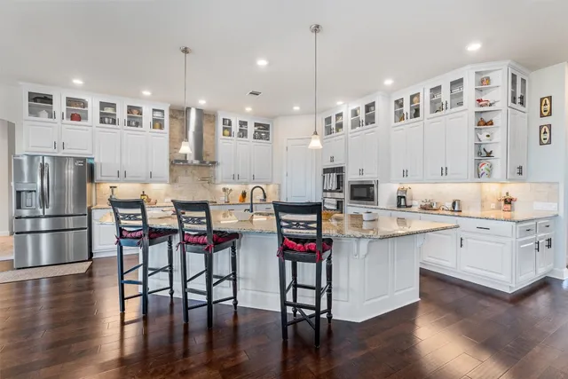 a kitchen with stainless steel appliances kitchen island granite countertop a table chairs stove and white cabinets
