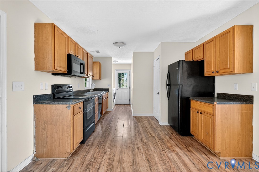 1611 Howerton Road Dunnsville, VA 22454 - Photo 17 of 36 a kitchen with stainless steel appliances granite countertop a refrigerator a stove top oven a sink and dishwasher with wooden floor