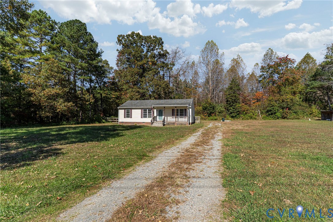 1611 Howerton Road Dunnsville, VA 22454 - Photo 30 of 36 a view of a house next to a yard with plants and large trees