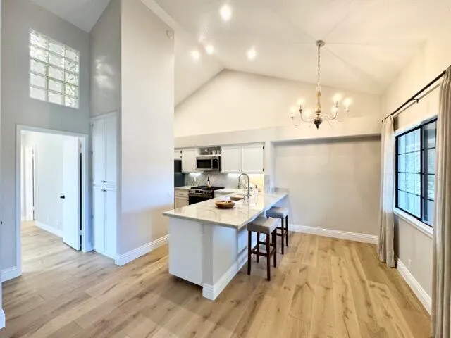 a room with stainless steel appliances kitchen island a table chairs in it and wooden floors