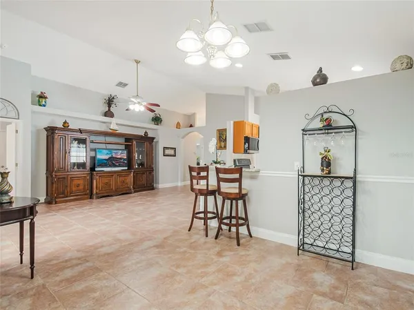 a view of an empty room with window and chandelier fan