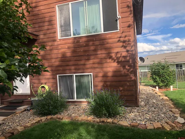 a view of a brick house with a yard and large tree