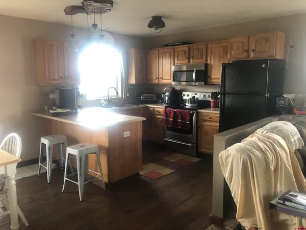 a kitchen with stainless steel appliances granite countertop a stove a refrigerator a sink a dining table and chairs with wooden floor