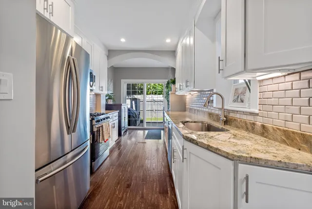 a kitchen with kitchen island granite countertop a sink appliances cabinets and a large window