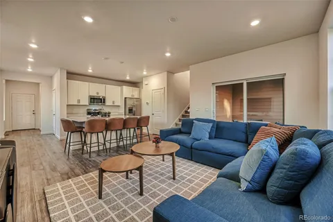 a living room kitchen with a couch and a dining table with wooden floor