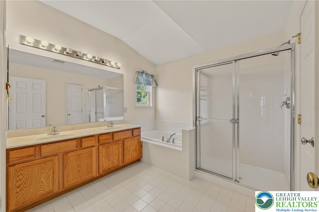 4345 Creek Road Allentown, PA 18104 - Photo 21 of 33 A well-lit primary bathroom featuring a double vanity, a soaking tub, and a separate walk-in shower.