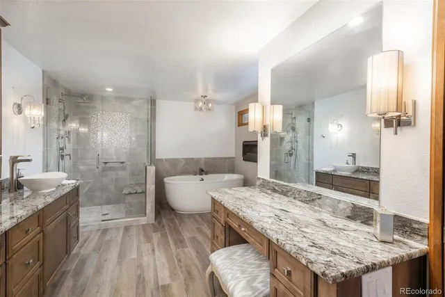 a bathroom with a granite countertop sink a toilet a mirror and shower