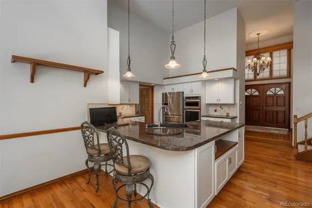 a kitchen with stainless steel appliances kitchen island granite countertop a table chairs in it and wooden floors