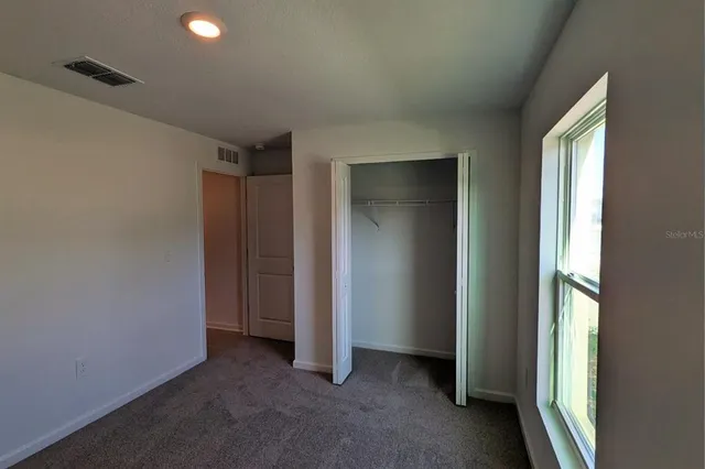 an empty room that has a large window and closet area