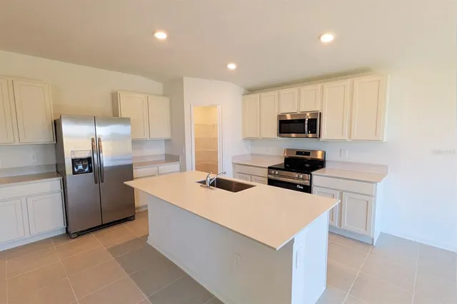 a kitchen with a sink a microwave a refrigerator and cabinets