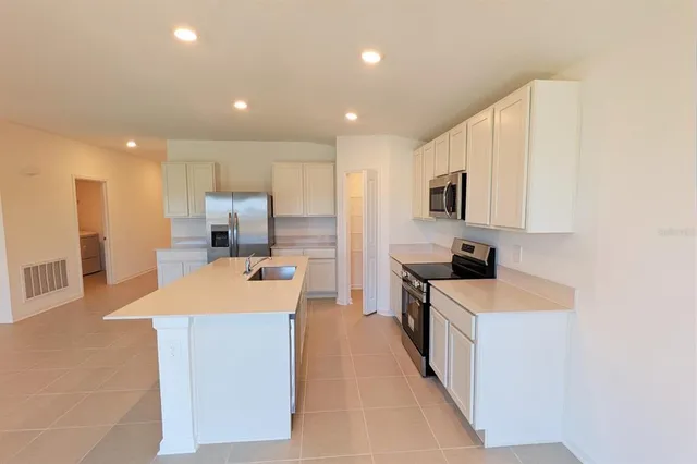 a large kitchen with kitchen island a sink a stove a refrigerator and a counter top space