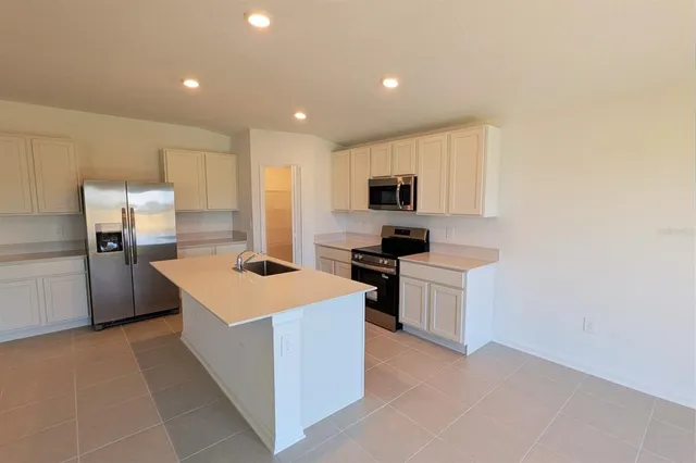 a kitchen with stainless steel appliances a sink stove refrigerator and cabinets