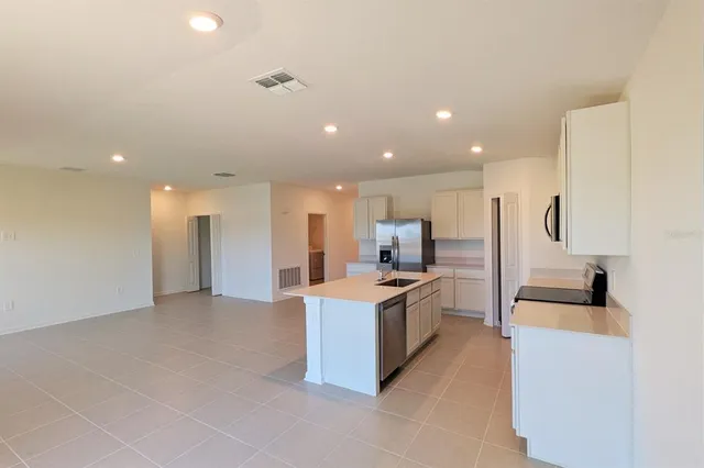 a living room with stainless steel appliances furniture a rug and a kitchen view