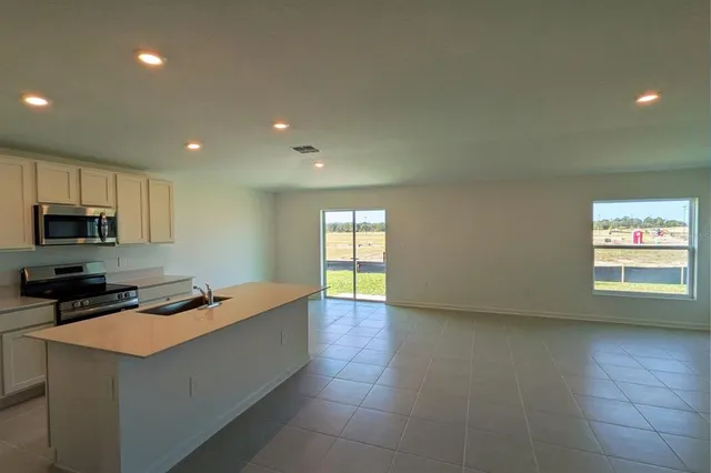 a kitchen with granite countertop a sink a counter top space cabinets and stainless steel appliances