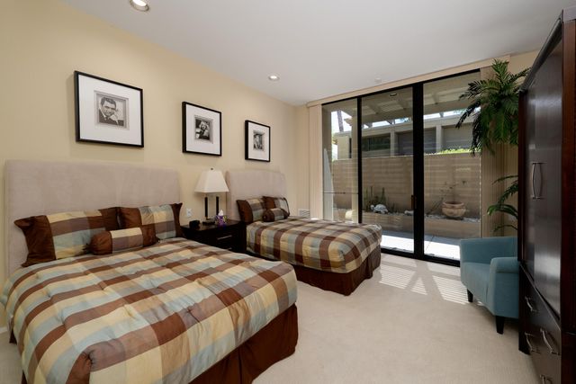 a view of a patio with a table chairs potted plants and palm trees