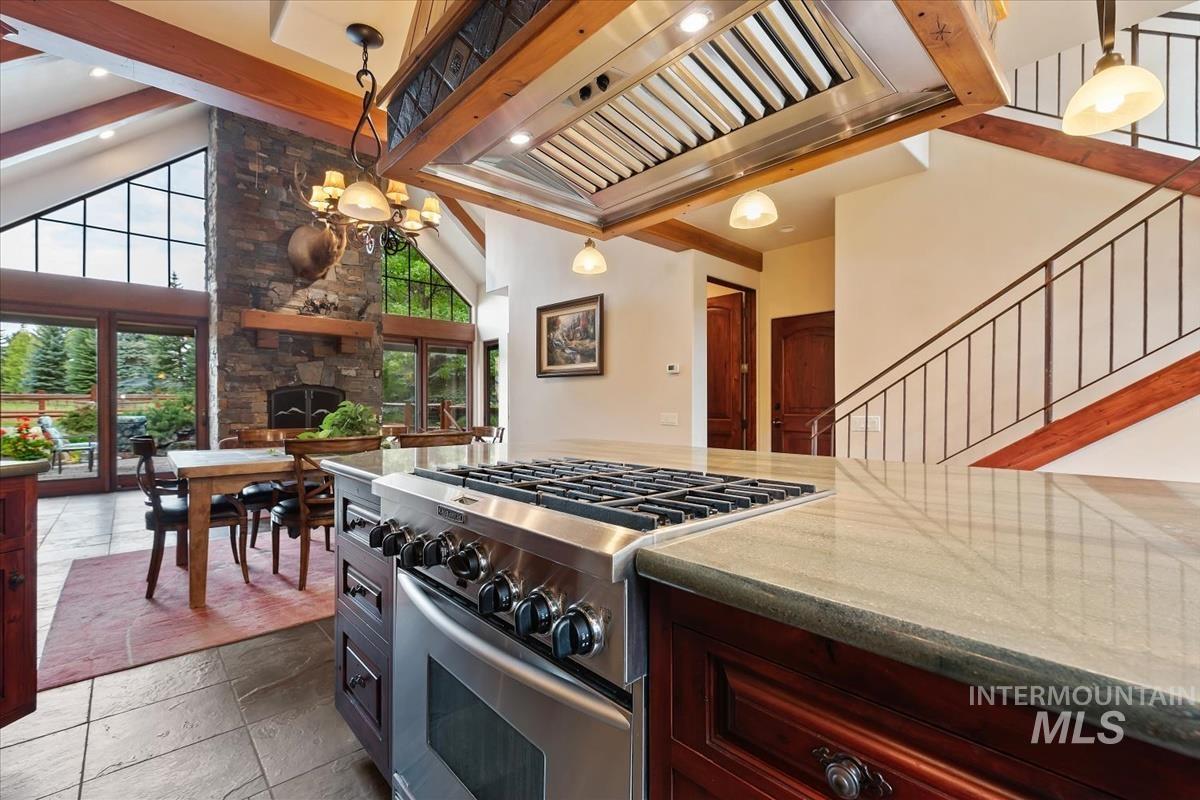 106 Hidden Hollow Road Hailey, ID 83333 - Photo 29 of 49 Stainless steel range with a built-in oven, stone countertops, exposed wood beams, a stone fireplace, and large glass pane windows