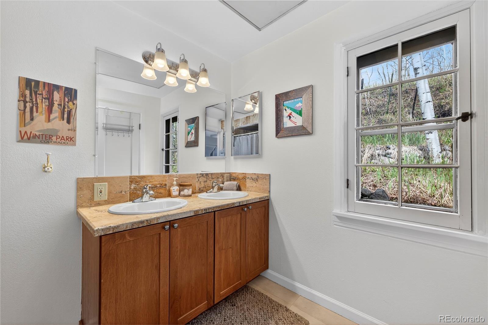 327 Vasquez Road, Unit E1 Winter Park, CO 80482 - Photo 25 of 43 a bathroom with a sink a large mirror and a window