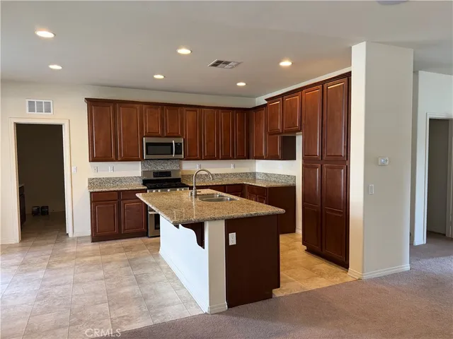a kitchen with kitchen island granite countertop stainless steel appliances and refrigerator