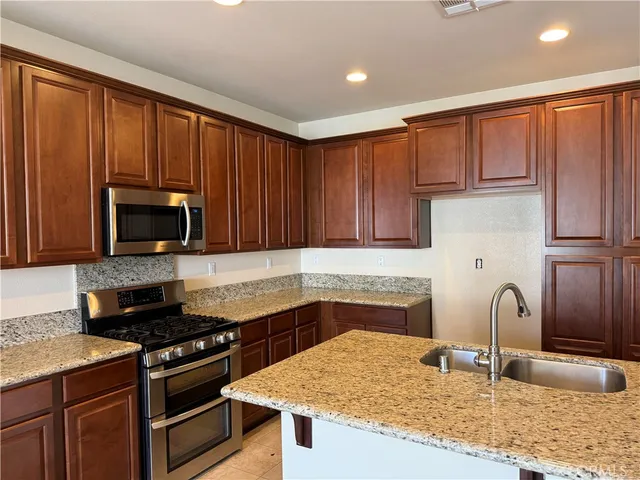 a kitchen with granite countertop a stove top oven sink and cabinets