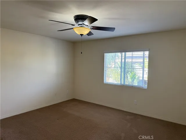 an empty room with a chandelier fan and windows