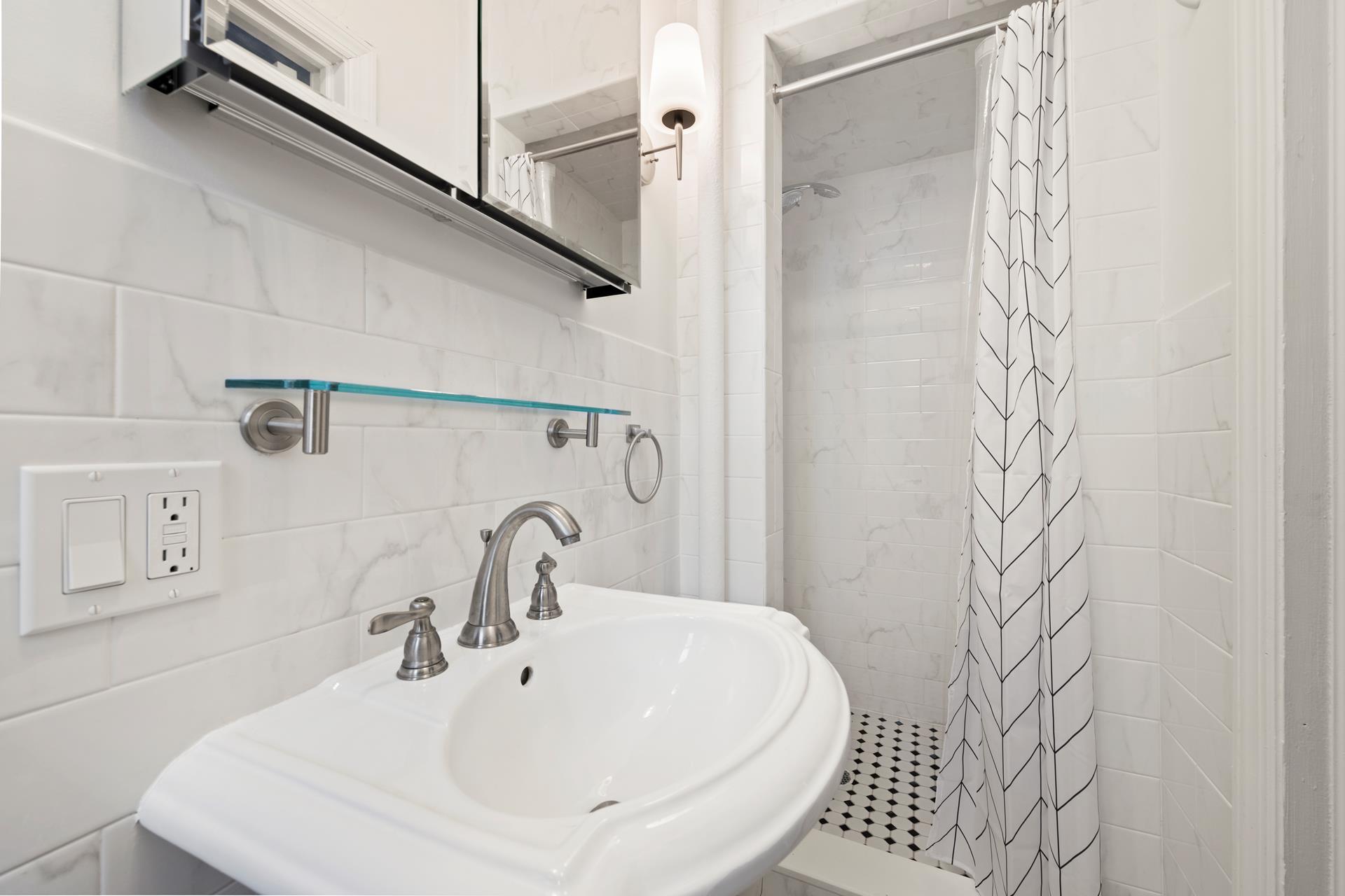 86-10 34th Avenue, Unit 113 Queens, NY 11372 - Photo 7 of 13 a bathroom with a sink and mirror with bathtub