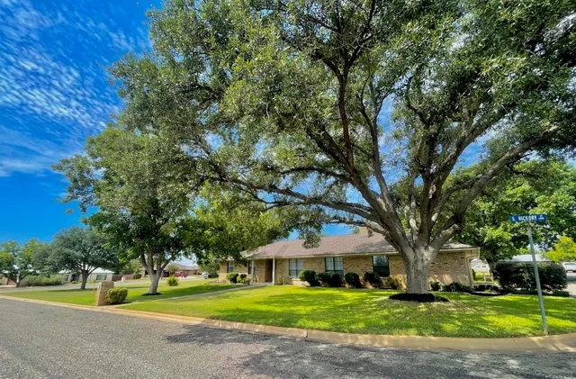 a front view of a house with garden and trees
