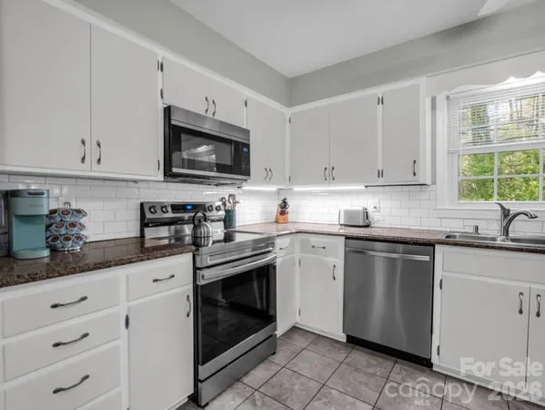 a kitchen with granite countertop white cabinets sink and stainless steel appliances