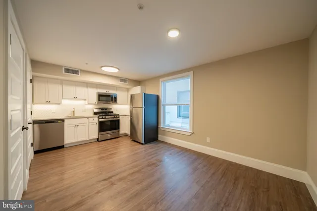a view of a kitchen with refrigerator and wooden floor