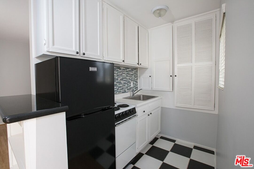 25 Spinnaker Street, Unit 12 Marina del Rey, CA 90292 - Photo 22 of 29 a kitchen with granite countertop white cabinets and black appliances