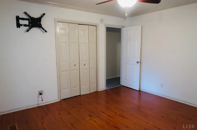 a view of an empty room with wooden floor and window
