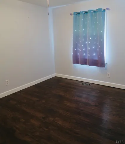 a view of an empty room with wooden floor and closet