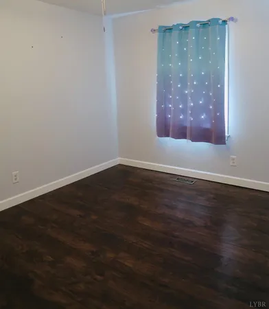 a view of an empty room with wooden floor and closet
