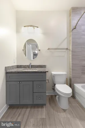 a bathroom with a granite countertop toilet sink and mirror