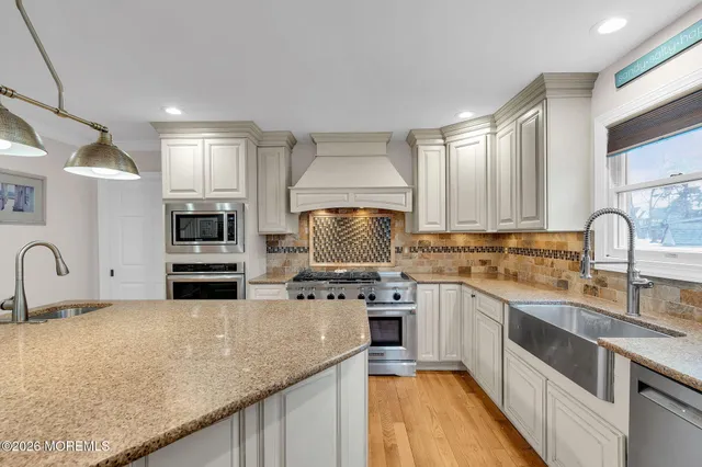 a kitchen with stainless steel appliances granite countertop a sink a stove and a wooden floors