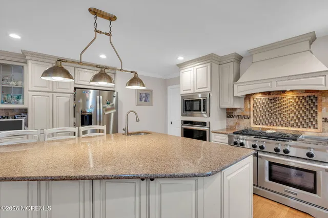 a kitchen with stainless steel appliances granite countertop a sink a refrigerator and a stove