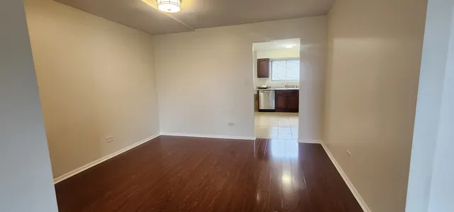 a view of a hallway with wooden floor and a kitchen
