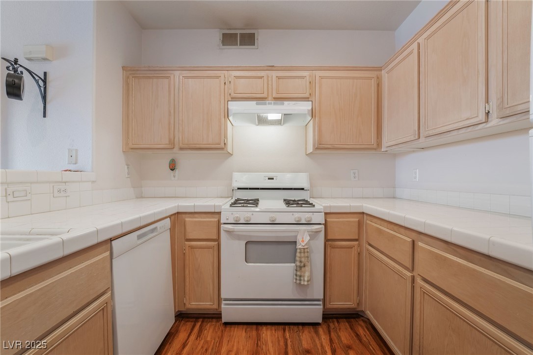 2201 Ramsgate Drive, Unit 823 Henderson, NV 89074 - Photo 8 of 31 Kitchen with visible vents, light brown cabinets, under cabinet range hood, dark wood finished floors, and white appliances