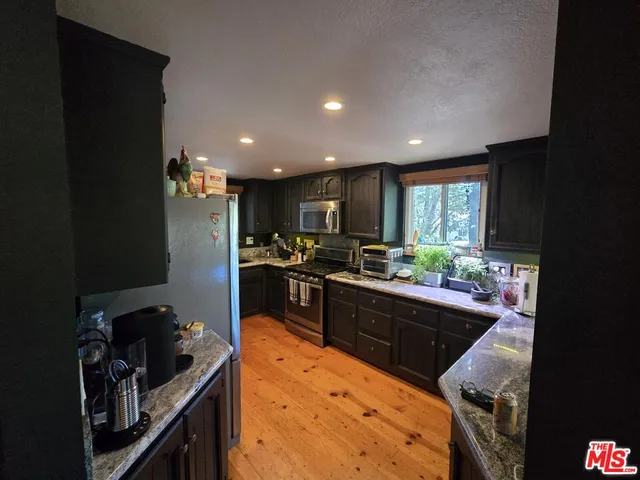 a kitchen with stainless steel appliances kitchen island granite countertop a refrigerator and a stove top oven