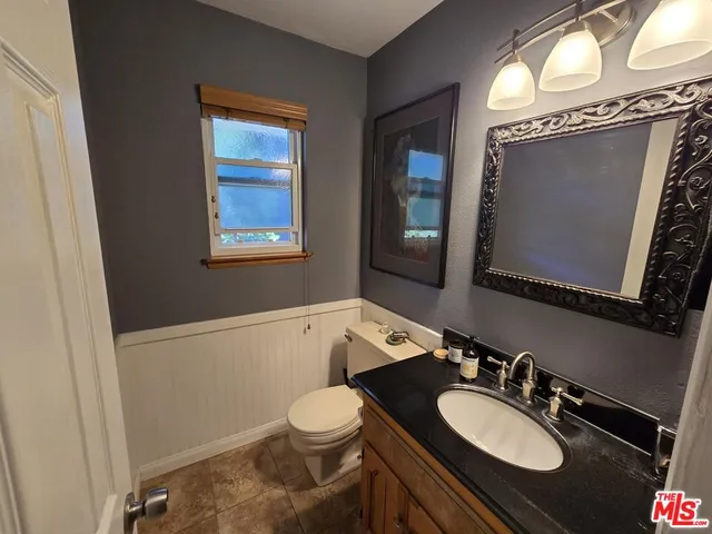 a bathroom with a granite countertop sink toilet mirror and bathtub