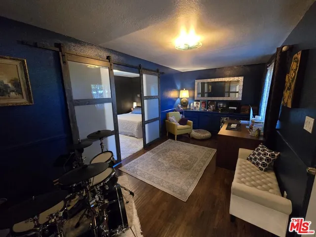 a living room with furniture a flat screen tv and a refrigerator