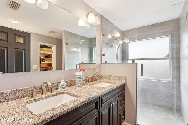 a bathroom with a granite countertop sink a large mirror and a shower