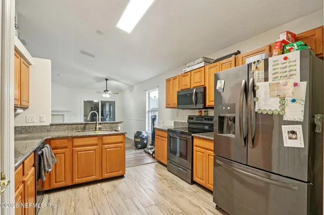 a kitchen with stainless steel appliances granite countertop wooden cabinets a sink and dishwasher with wooden floor