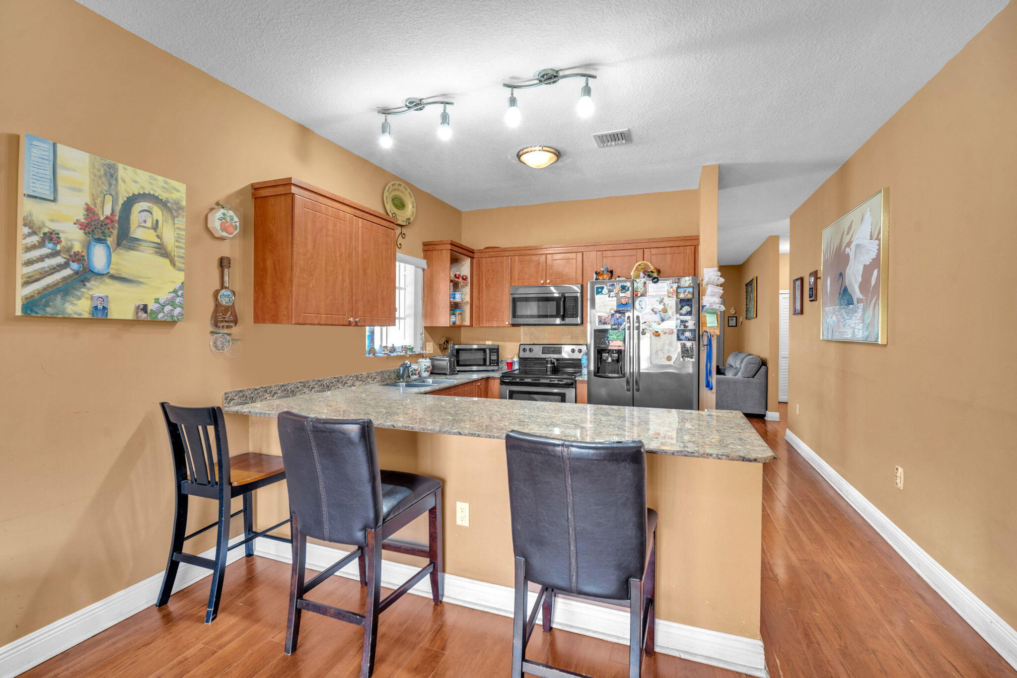 1395 West 30th Street Hialeah, FL 33012 - Photo 2 of 26 a kitchen with stainless steel appliances kitchen island granite countertop a dining table chairs and a refrigerator