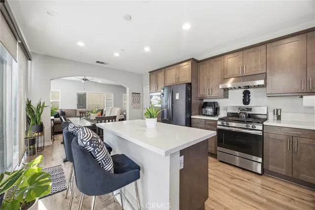 a kitchen with stainless steel appliances kitchen island a table chairs and a refrigerator
