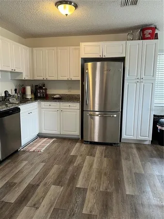 a kitchen with granite countertop a refrigerator sink and cabinets
