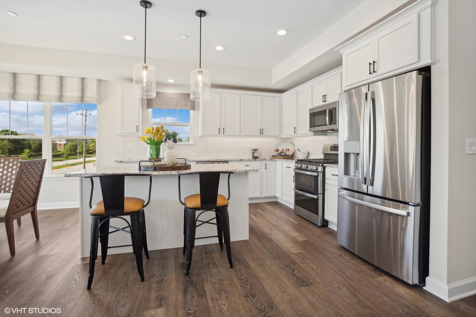 327 Masters Drive Addison, IL 60101 - Photo 5 of 16 a kitchen with stainless steel appliances granite countertop a table chairs wooden floors a refrigerator and a stove top oven