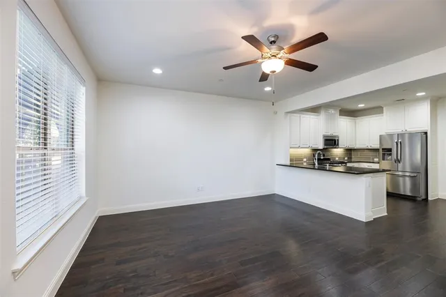 a view of an empty room with kitchen view and a window