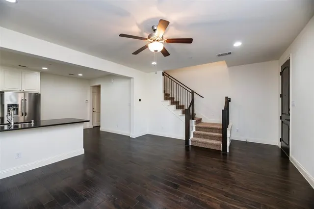 a view of an empty room with wooden floor and a ceiling fan