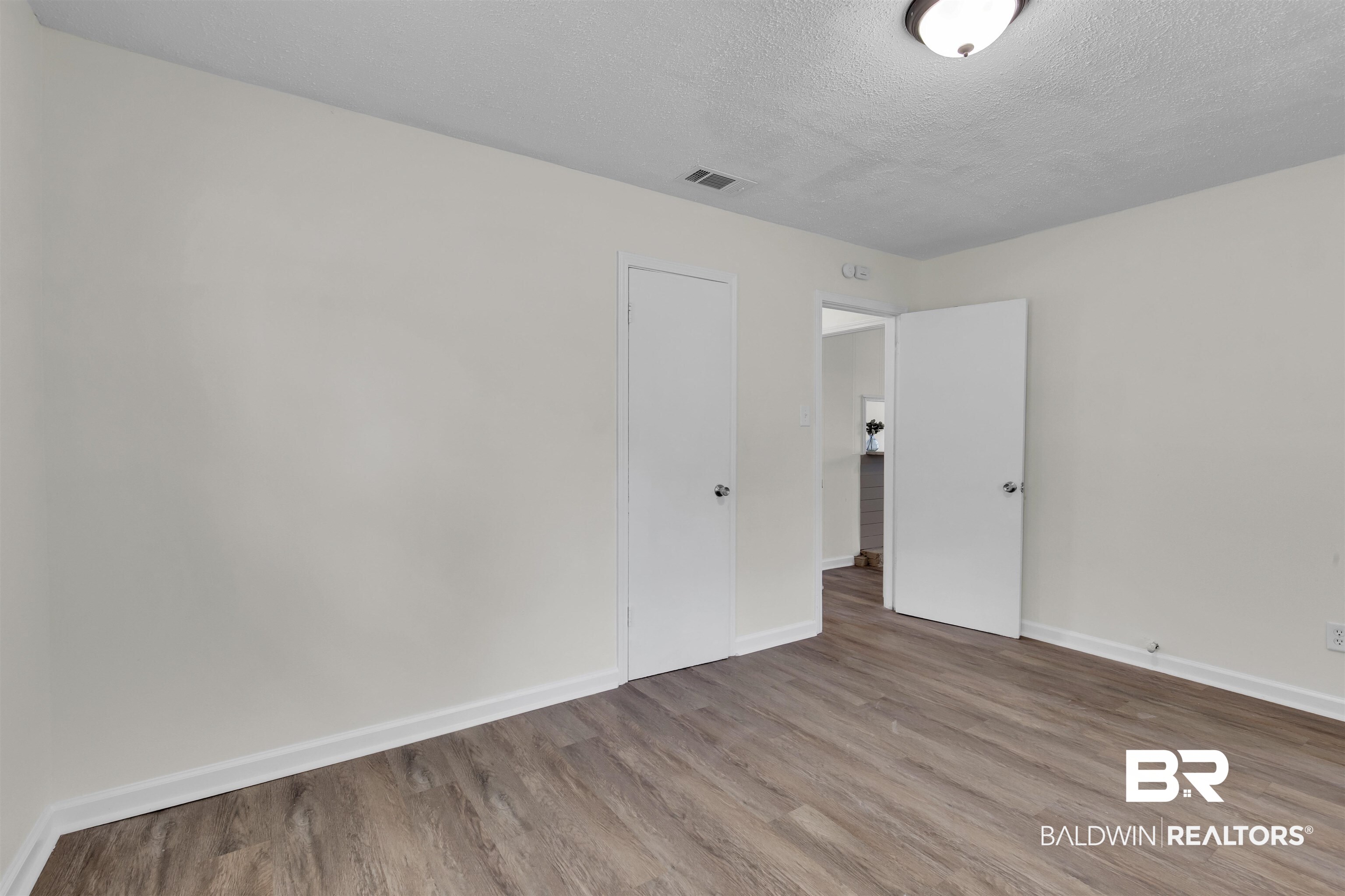 9241 Vallaris Street North Mobile, AL 36608 - Photo 5 of 17 Unfurnished bedroom with a textured ceiling, wood finished floors, visible vents, and baseboards