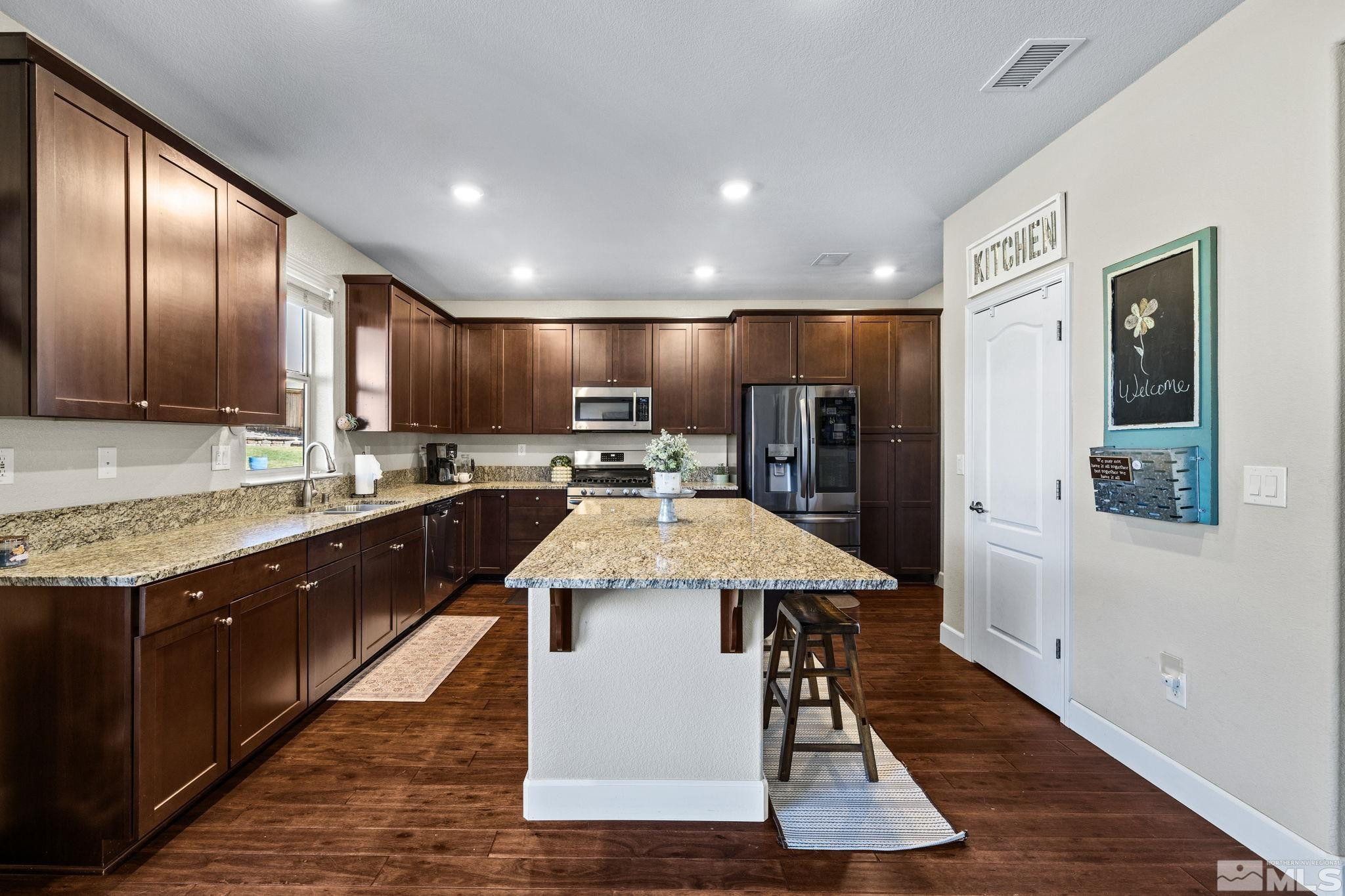 1735 Samantha Crest Trail Reno, NV 89523 - Photo 7 of 32 a large kitchen with stainless steel appliances kitchen island granite countertop a stove a sink dishwasher and a refrigerator with wooden floor